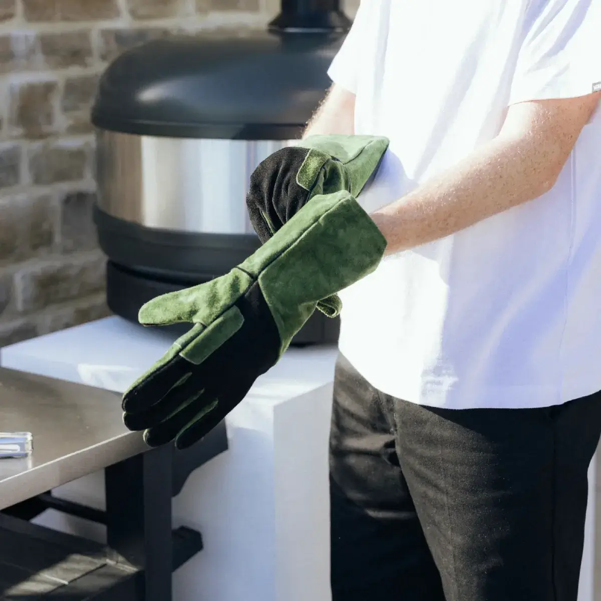 Persona poniéndose los guantes Gozney de ante para cocina exterior