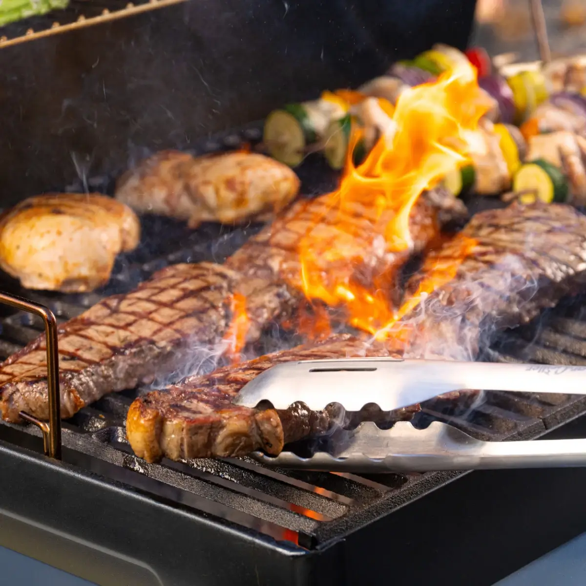Pinzas para parrilla Char-Griller manipulando alimentos durante la cocción