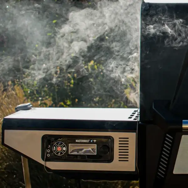 Equipo Masterbuilt Gravity Series funcionando al aire libre con humo alrededor del panel de control.