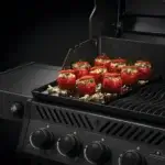 Plancha Napoleon 56426 instalada en una Freestyle 425 cocinando tomates rellenos con queso y hierbas.