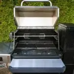 Kit rostizador instalado en una parrilla Masterbuilt Gravity Series abierta en un entorno exterior.
