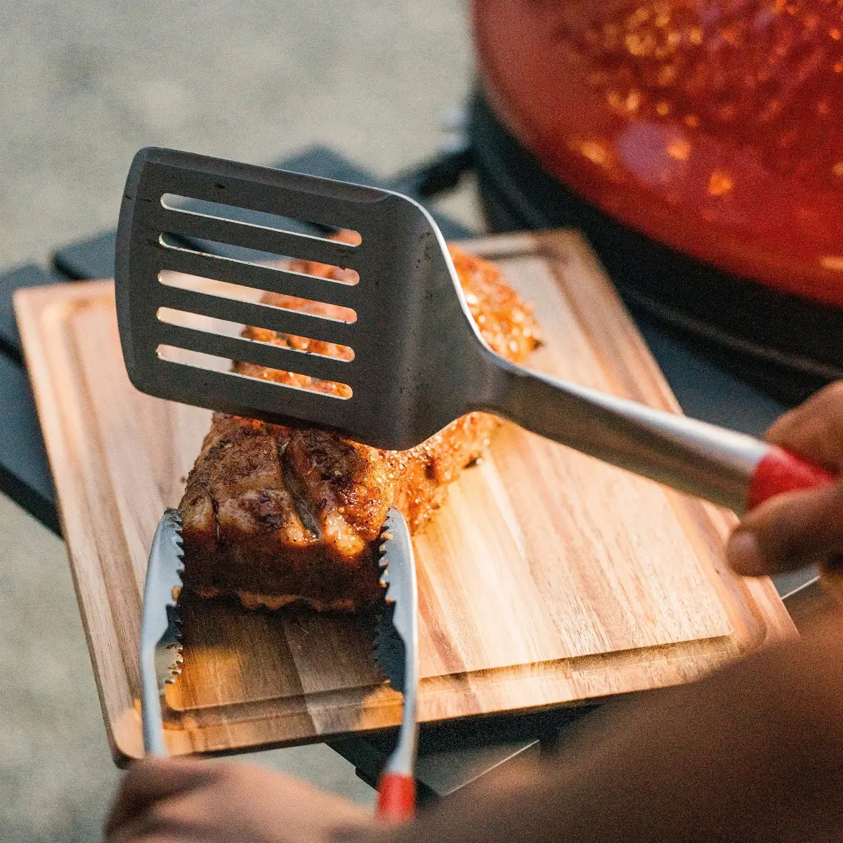 Espátula Kamado Joe cortando y separando carne sobre tabla de madera