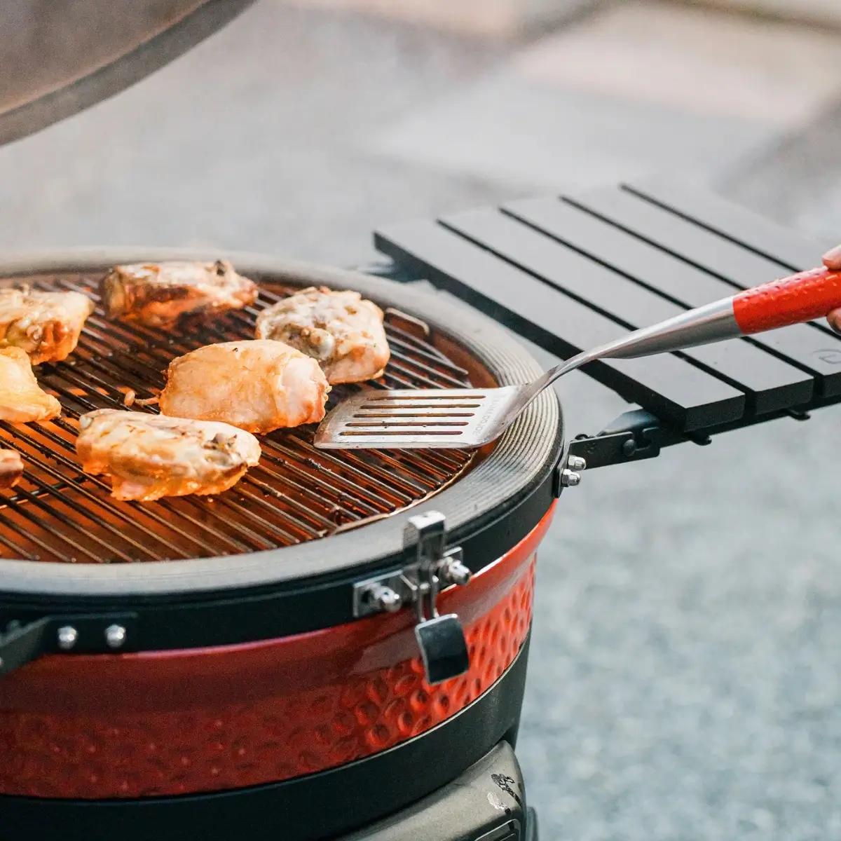 Grilled chicken thighs being handled with a Kamado Joe spatula